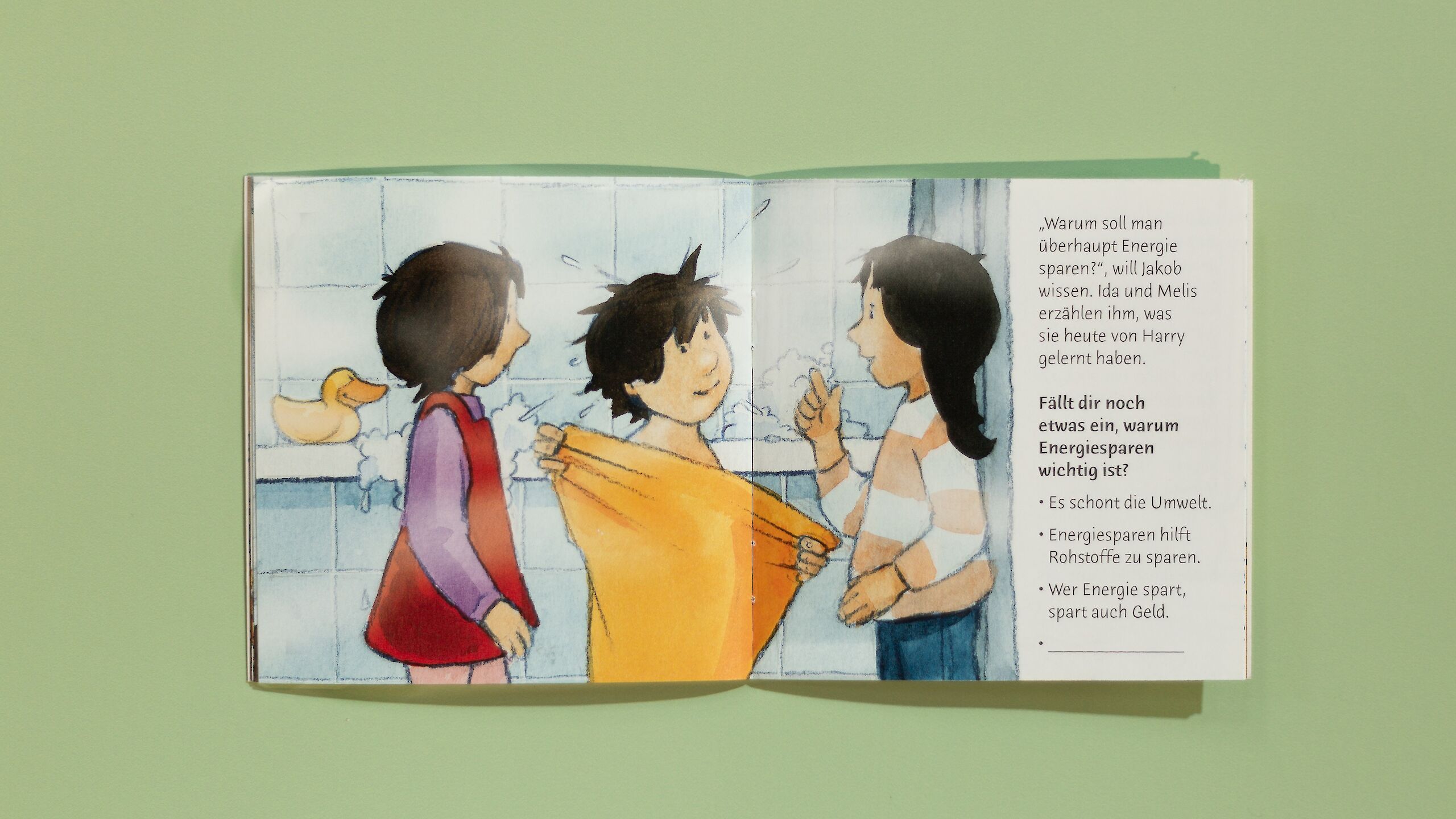 Das Bild zeigt eine Illustration aus einem Pixi-Buch. Drei Kinder stehen in einem Badezimmer. Eines der Kinder wird in ein Handtuch gewickelt, während die anderen etwas erklären. Rechts auf der Seite steht ein Text über Energiesparen.
