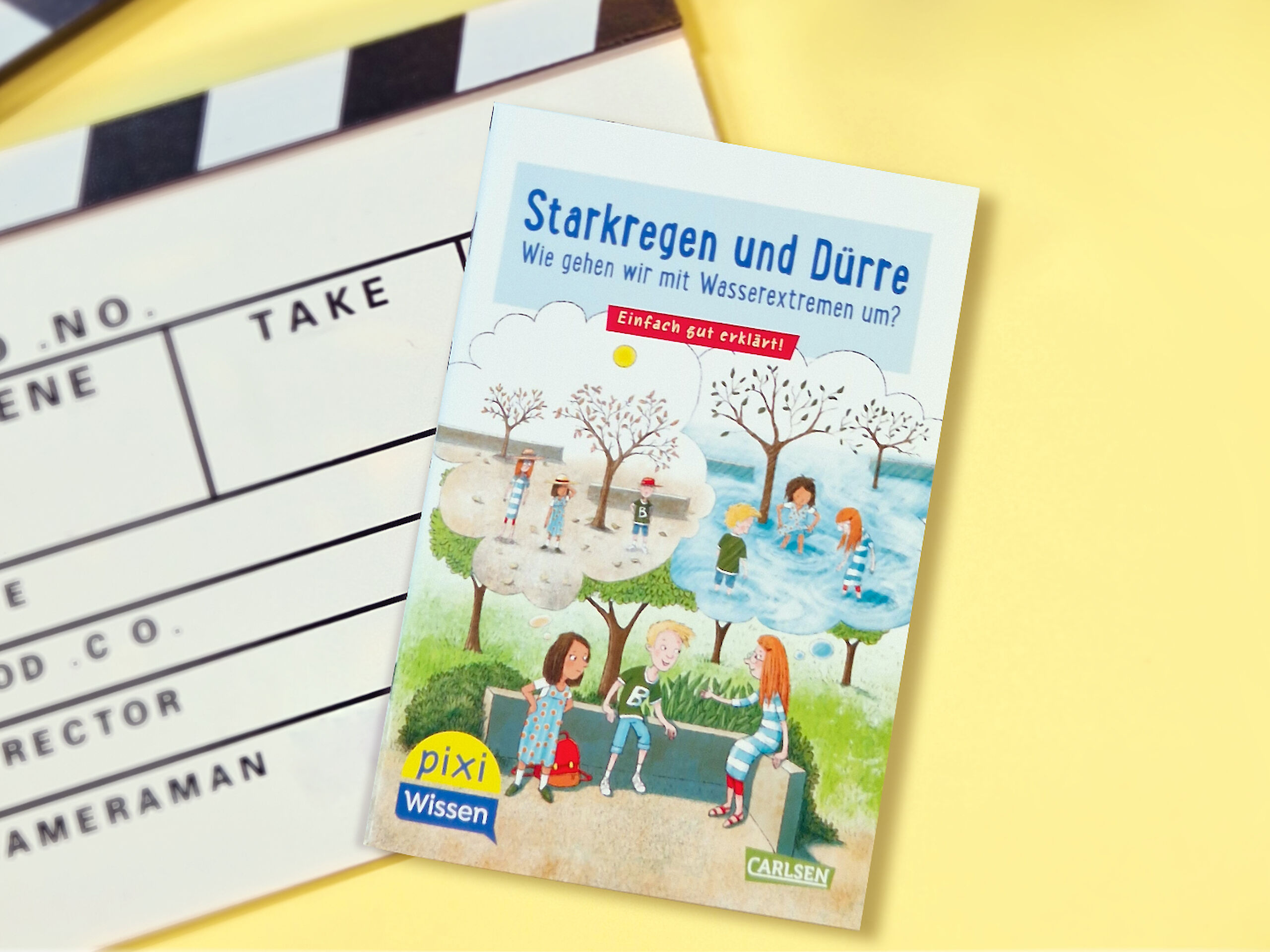 Pixi Wissen Buch „Starkregen und Dürre“ liegt neben einer Filmklappe auf gelbem Hintergrund; Motiv für ein erklärendes Video zum Umgang mit Wetterextremen.